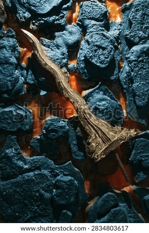 A dramatic close-up of a rugged metallic axe resting among dark, charred volcanic rocks surrounded by glowing orange molten lava. The contrasting textures of rough black stones, flowing lava, and the intricately patterned metal axe create a powerful atmosphere of heat, destruction, and resilience. Strong warm and cool color contrast emphasizes the intense volcanic environment, while detailed surface textures give the scene a cinematic and realistic appearance.