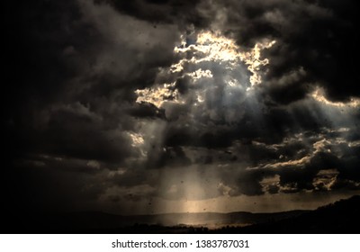 Dramatic cloud during a storm, rain drops in the air,sun rays, sun lit landscape. 