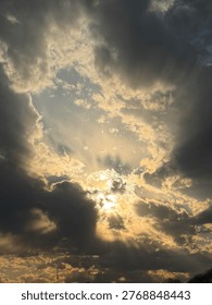 Dramatic cloud formation showcases sunlight breaking through, casting rays of light against a backdrop of contrasting dark and light clouds