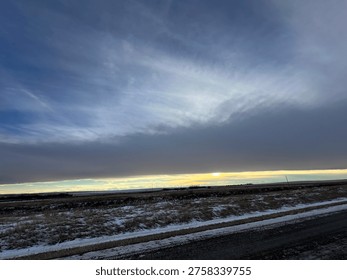 Dramatic cloud formation stretching across the sky above an open prairie landscape, capturing changing weather conditions and natural scenery in Strathmore, Alberta, Canada.