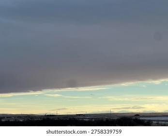 Dramatic cloud formation stretching across the sky above an open prairie landscape, capturing changing weather conditions and natural scenery in Strathmore, Alberta, Canada.