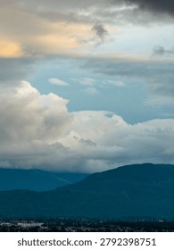 Dramatic cloud layers and soft light above forested mountains and urban edge near Chilliwack, British Columbia, Canada.