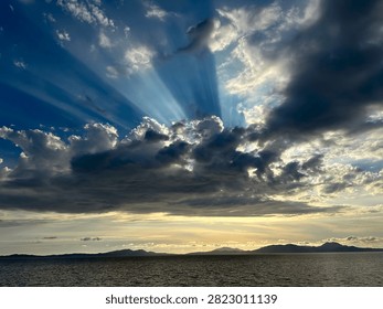 A dramatic cloud pierced by the sun's rays over the Ionian Sea