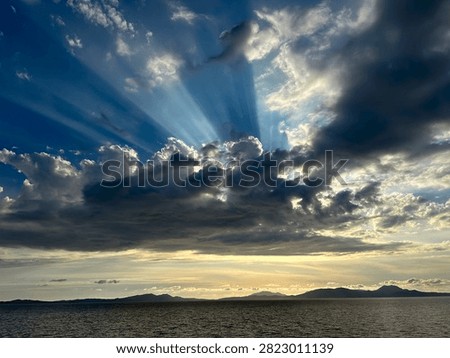 A dramatic cloud pierced by the sun's rays over the Ionian Sea
