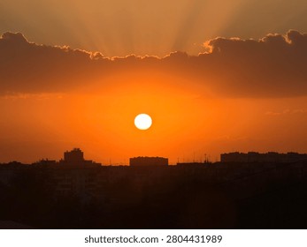 Dramatic clouds catch the last rays of sunlight as dusk settles over the dense metropolitan cityscape.