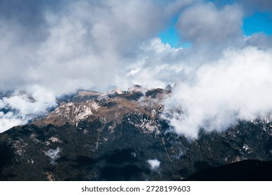 Dramatic clouds drift across the rugged peaks of Seceda in the Italian Dolomites, revealing glimpses of the alpine landscape below