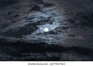 Dramatic clouds in the moonlight. Full moon in the night sky.