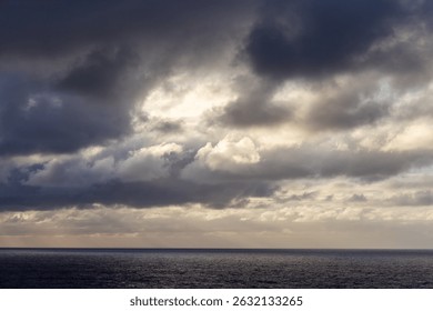 Dramatic clouds over the calm Pacific Ocean horizon, evoking tranquility and mystery.