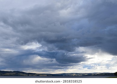 Dramatic clouds over Mjøsa lake in Hamar, Norway with soft light breaking through and calm atmosphere