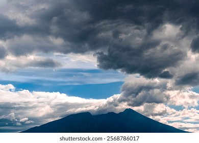 Dramatic clouds over a mountain peak with vibrant blue sky.