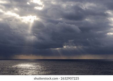 Dramatic clouds over the Pacific Ocean with radiant sun rays breaking through.