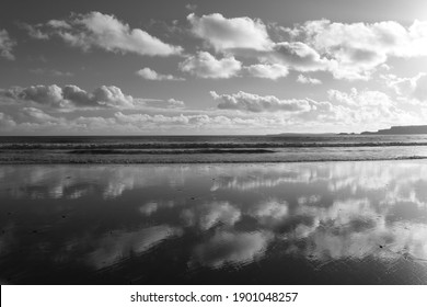 Dramatic clouds reflected in the wetsand on the beach at Amroth, Pembrokeshire, Wales, UK.