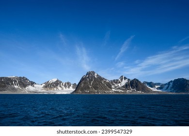 Dramatic clouds in the sky above the mountain peaks in Smeerenburg Fjord, Svalbard, in the summer arctic
					
