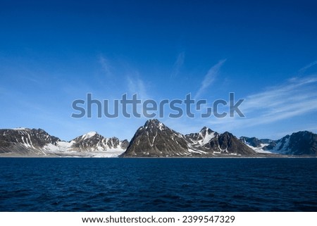 Dramatic clouds in the sky above the mountain peaks in Smeerenburg Fjord, Svalbard, in the summer arctic

