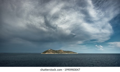 Dramatic Clouds And Sky Over Stormy Sea At Sunset With Island On Horizon.