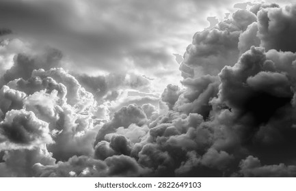 Dramatic clouds and a stormy sky captured in black and white, showcasing a powerful weather phenomenon with majestic cumulus clouds building up.