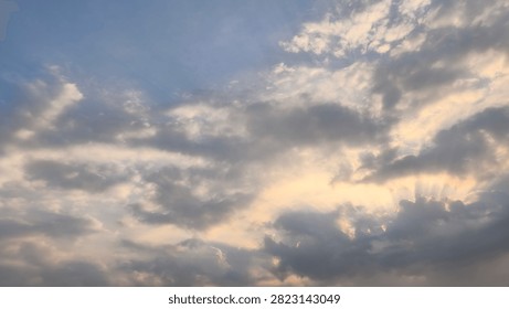 Dramatic clouds with sunset light rays breaking through in the blue evening sky.