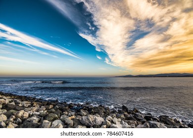 Dramatic clouds at sunset on the rocky beach