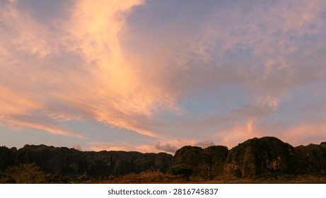 Dramatic clouds at sunset or sunrise, tinged with a blend of yellow, orange, and reddish hues.