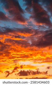 Dramatic clouds at sunset or sunrise. Vibrant orange clouds at sunset vertical photo.