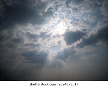 Dramatic clouds swirl around a bright, piercing sun