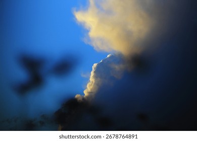 
Dramatic cloudscape with golden sunlight illuminating the tops of cumulus clouds against a clear blue sky.