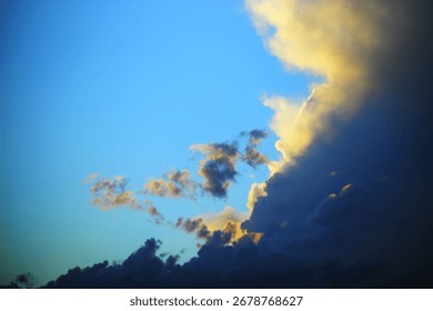 Dramatic cloudscape with golden sunlight illuminating the edges of dark storm clouds against a deep blue sky.