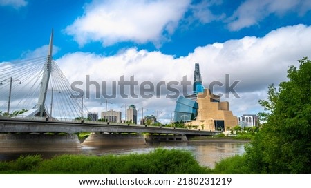 Dramatic cloudscape and landscape with the views of Esplanade Riel Footbridge and The Canadian Museum for Human Rights over the Red River in Winnipeg, Canada.