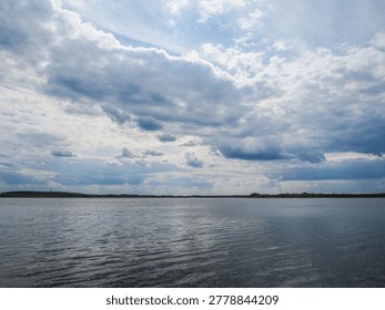 Dramatic Cloudscape Over Calm Lake with Wide Blue Sky and Distant Horizon