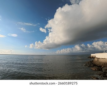 Dramatic Cloudscape Over Calm Ocean with Rocky Shoreline