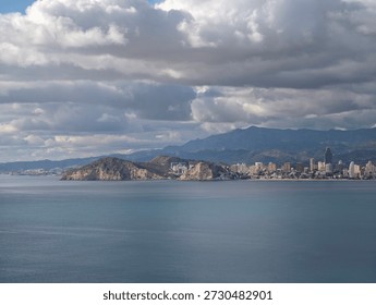 dramatic cloudscape over coastal cityscape atmospheric, towering clouds cast deep shadows over bay and towers,