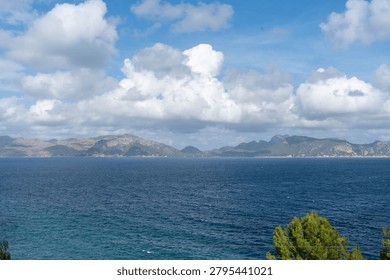 Dramatic cloudscape over deep blue sea and distant mountain coastline