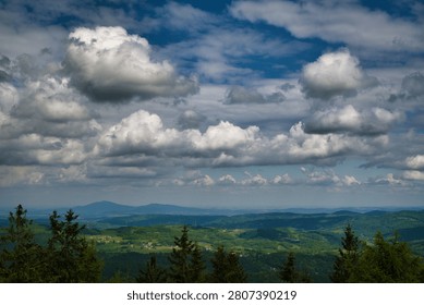 Dramatic cloudscape over green hills and the distant Chełmiec Mountain massif - Wałbrzych Mountains, Borowa Massif.