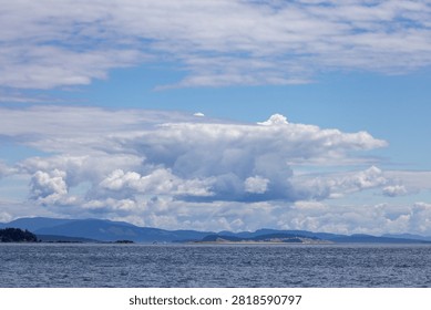 Dramatic cloudscape over the ocean near Sidney on Vancouver Island, BC, Canada, with distant islands and calm water.