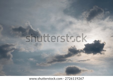 Dramatic cloudy sky background with sun hiding behind dark clouds