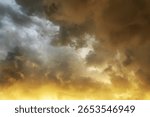 Dramatic cloudy sky during sunset with dark storm clouds and golden sunlight illuminating the horizon, creating a vibrant and moody atmospheric scene.