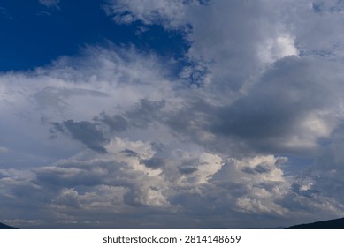 A dramatic cloudy sky featuring a mix of dark storm clouds and bright blue patches. This meteorological image is an excellent resource for adding mood and atmosphere to digital compositions.