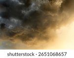 Dramatic cloudy sky with golden sunlight breaking through dark storm clouds during sunset, creating a moody atmospheric scene in nature.