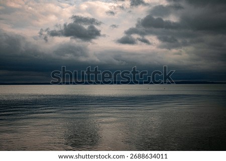 Dramatic cloudy sky over calm lake horizon at dusk  
Storm clouds above tranquil water – moody landscape scene  
Serene lake view with layered clouds and soft reflections  
Peaceful Balaton scenery 