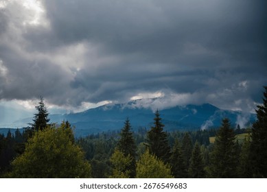 Dramatic cloudy sky over a forested mountain landscape.