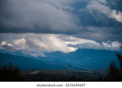 Dramatic cloudy sky over a mountain landscape with forested hills.