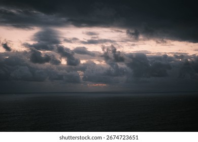 Dramatic cloudy sky over the ocean at sunset, with dark clouds and soft light on the horizon, capturing the beauty of seascape, weather, and atmospheric nature scenery.