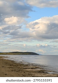 Dramatic Cloudy Sky Over Sandy Beach and Green Hills