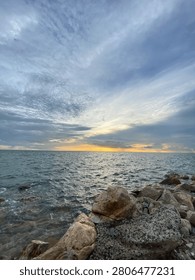Dramatic cloudy sky over the sea with rocky coastline at sunset