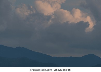 Dramatic cloudy sky over silhouetted mountain range at dusk, showcasing serene natural landscape and atmospheric weather conditions