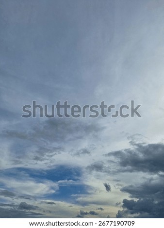 Dramatic cloudy sky with patches of blue and soft light, creating a natural abstract pattern in the atmosphere.