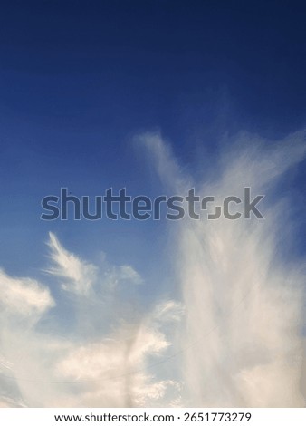 Dramatic cloudy sky with soft white wisps and deep blue tones, perfect for backgrounds, Nature Themes, and peaceful sky concepts.