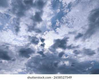 Dramatic Cloudy Sky with Sunlight Breaking Through. Dynamic cloudscape with dense gray and white clouds covering the sky, allowing rays of sunlight to pierce through.