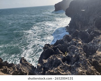Dramatic coastal cliffs with ocean waves crashing below, captured in natural daylight. A scenic seascape showcasing rugged rock formations and the power of the sea