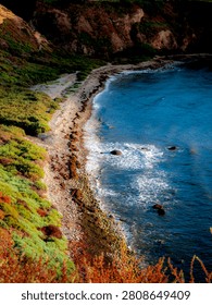 A dramatic coastal landscape showcasing the rugged cliffs meeting the vibrant blue waters of Lunada Bay, with waves gently lapping the shore